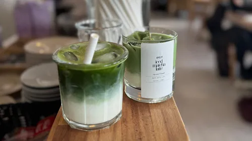 Two glasses of iced matcha lattes in cafe.