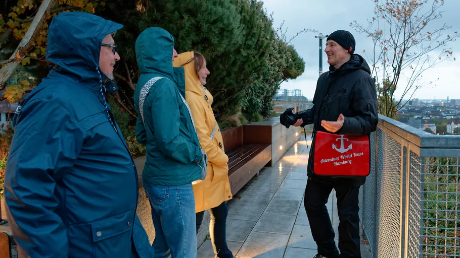Gruppe in Regenmänteln hört einem Führer zu.