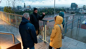 Gruppe von Menschen blickt von Dach auf die Stadt.