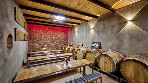 Barrels and tables in stone-walled wine cellar.
