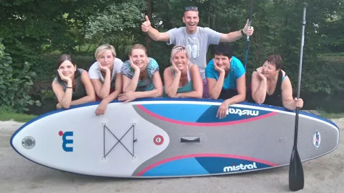 Group posing with paddleboard outdoors.