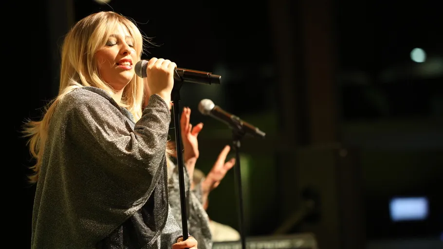 Woman singing into microphone on stage.