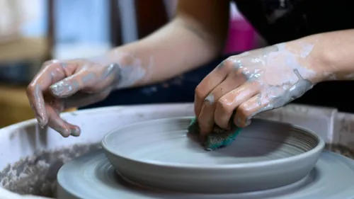 Hands shaping clay on potter's wheel.
