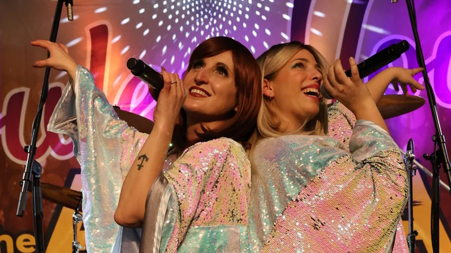 Two singers performing on stage with microphones.