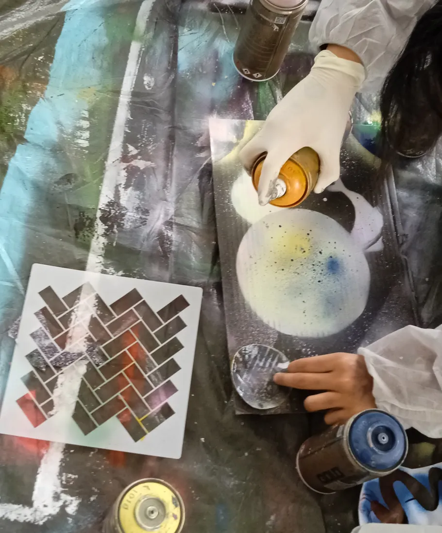 Person spray paints on canvas with stencil.