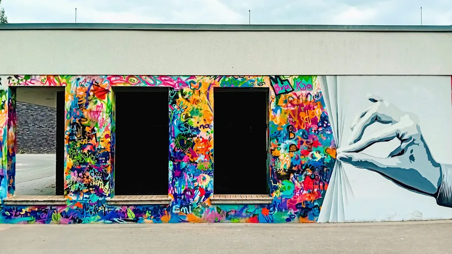Colorful graffiti wall with large hand drawing.