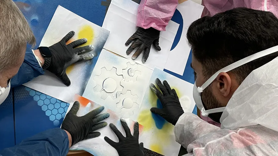People using stencils on a colorful table.