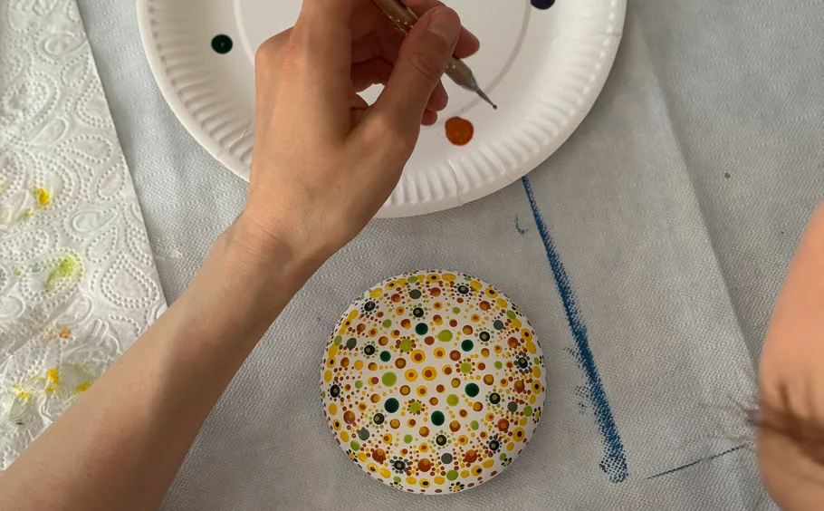 Hand painting colorful dots on ceramic plate.