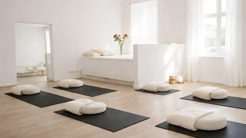 Meditationsraum mit Matten und Kissen, helle Atmosphäre.