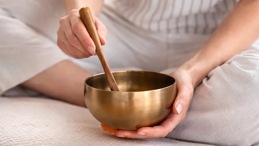 Person holding and playing a singing bowl.
