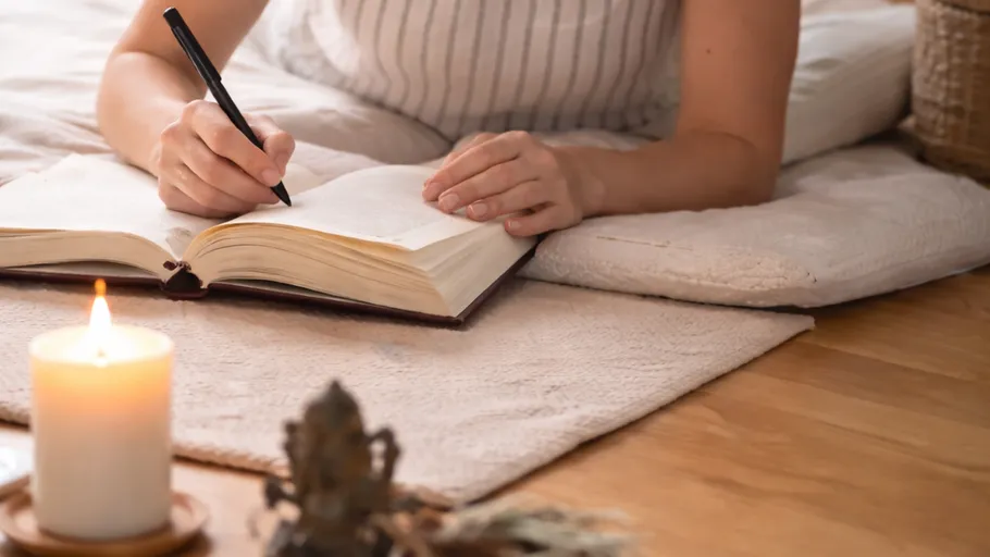 Person writing in journal by candlelight.