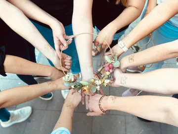 Hands hold a wreath of flowers in a friendly circle.
