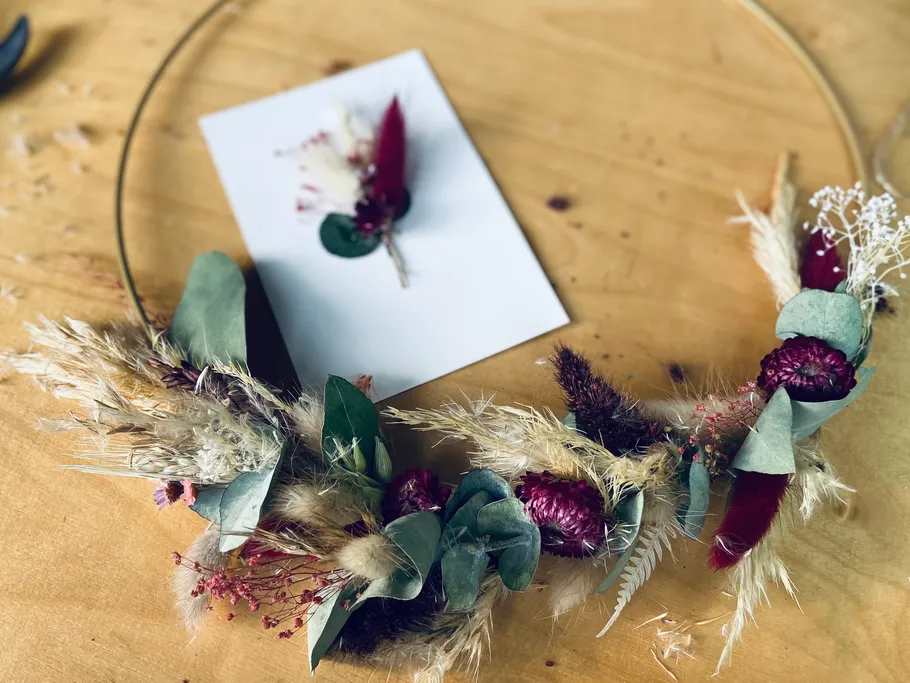 A wreath of flowers is lying on a table next to a paper card.