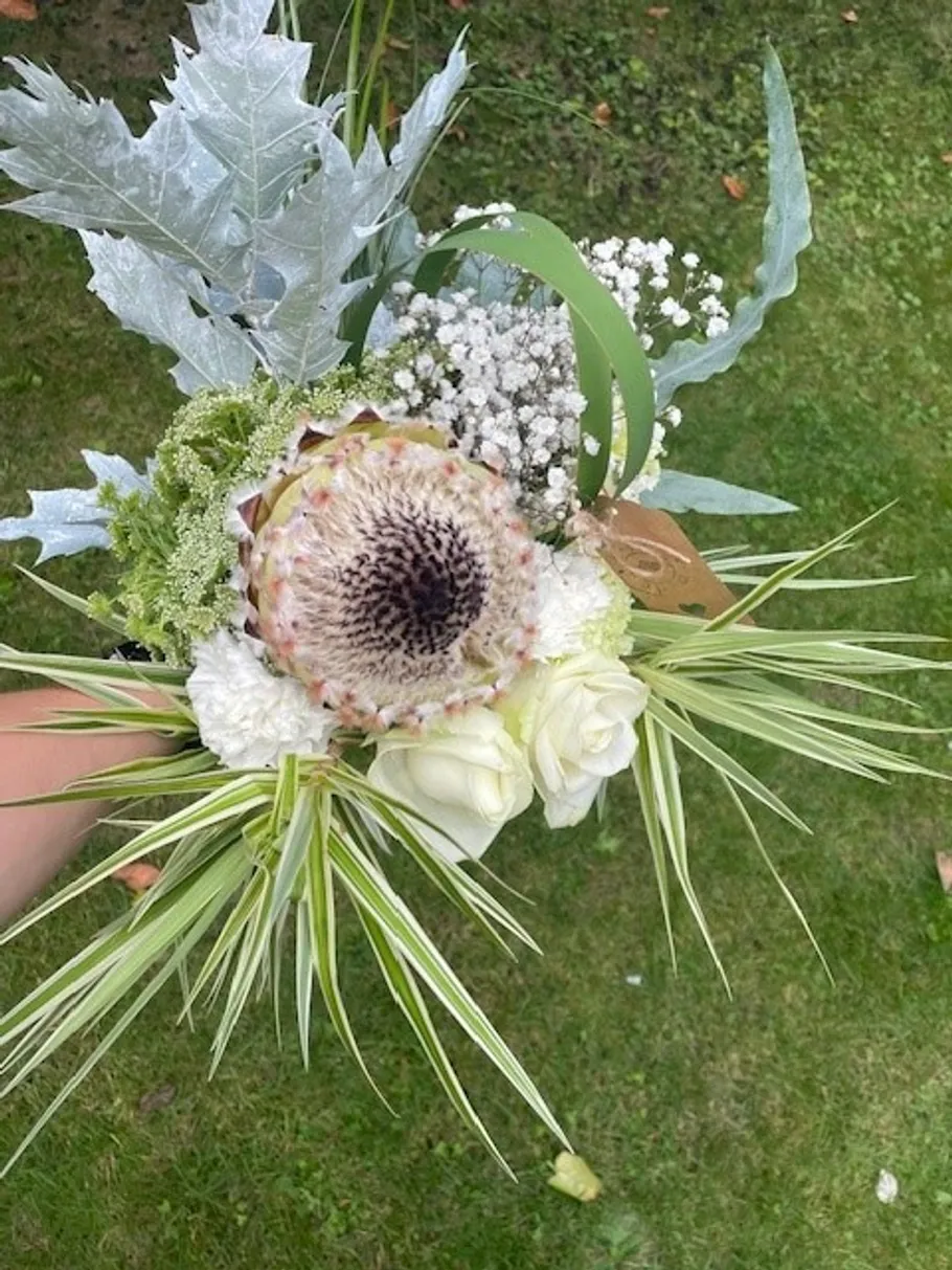 Blumenstrauß mit weißen Blumen auf Rasen.