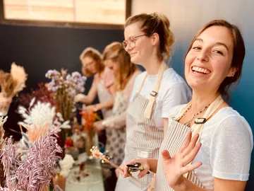 Several women create dried flower arrangements in a room.