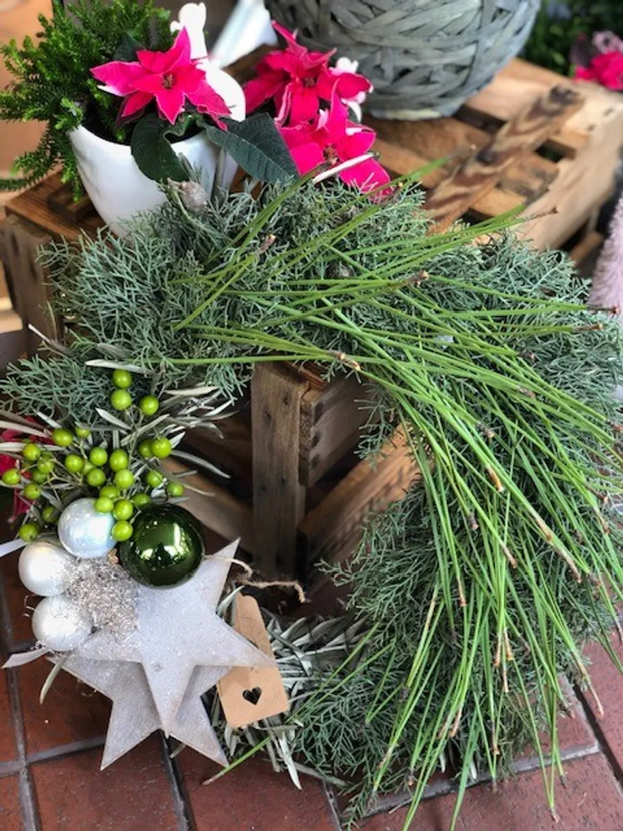 Green wreath with red flowers on wooden crates.