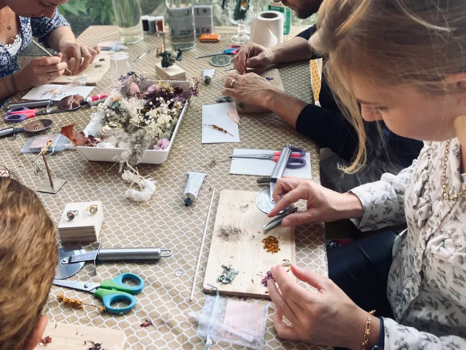 People make crafts together with dried flowers on a table.