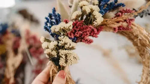 Hand holding colorful dried flower wreath.
