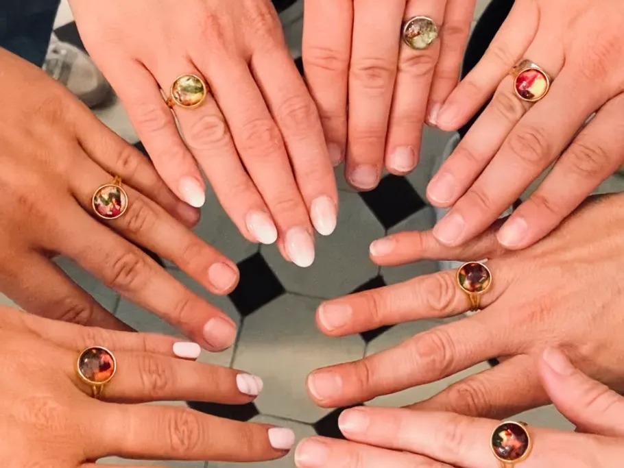 Hands with rings form a circle on a floor.