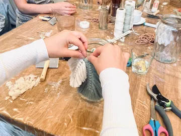Hände basteln Dekoration aus buntem Material am Tisch.