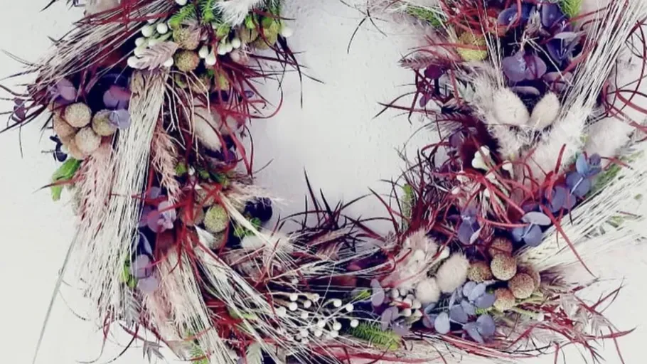 Colorful wreath with dried flowers on wall.
