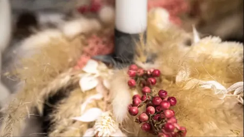 White candle with dried flowers and berries.