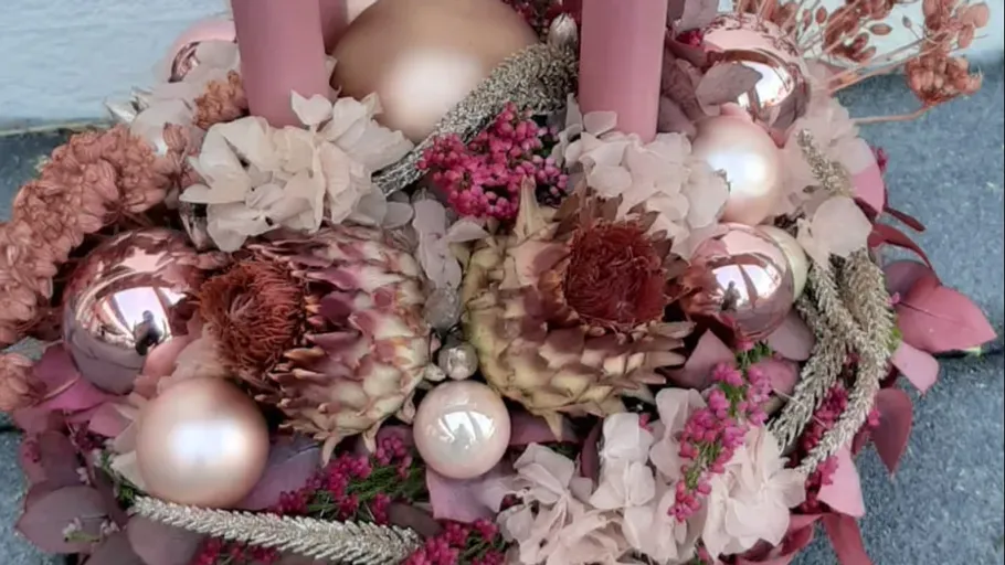 Floral arrangement with pink candles and ornaments.