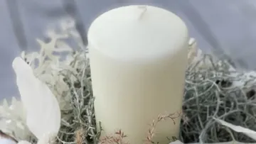 White candle on a decorative natural arrangement.