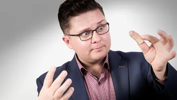 Man wearing suit, extending impressively large thumb.