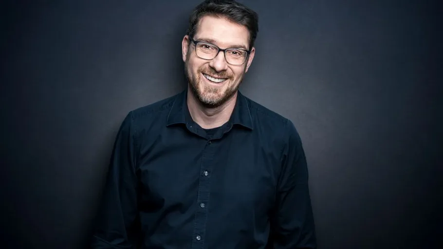 Man smiling against dark background.