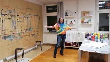 Frau im bunten Shirt posiert im Kunststudio.