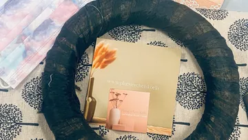 Black wreath lies on a patterned base with a brochure.