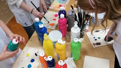 People painting with colorful bottles on table.