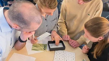 Gruppe löst Rätsel am Tisch mit Papieren.