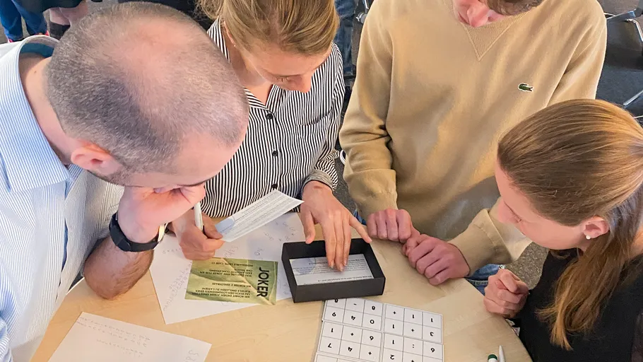 Group solving puzzle at table with papers.