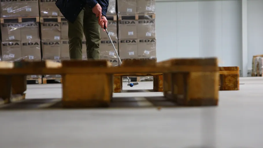 Person playing mini-golf in a warehouse.