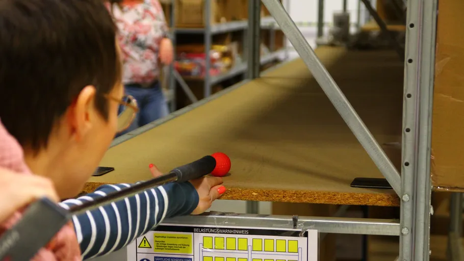 Person checking empty shelf with stick in warehouse.