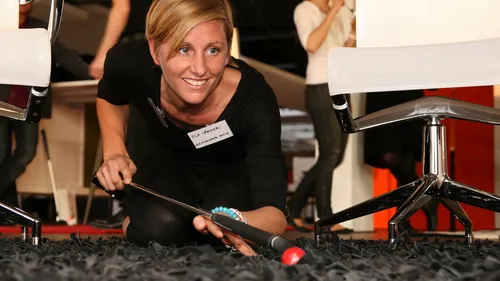 Lächelnde Frau spielt Krocket drinnen auf Teppich.