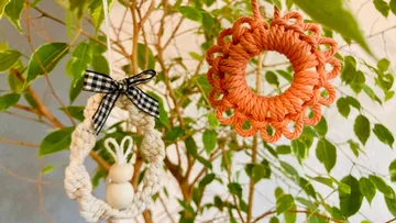 Two woven ornaments hanging on a tree.