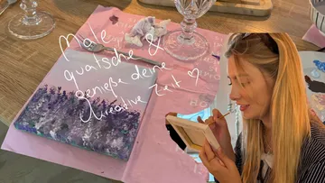 Woman painting on canvas at table.