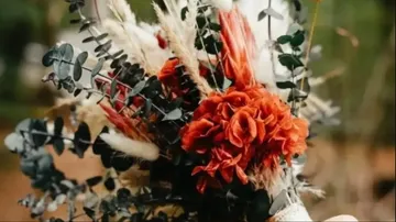Rustic bouquet with red flowers, foliage outdoors.