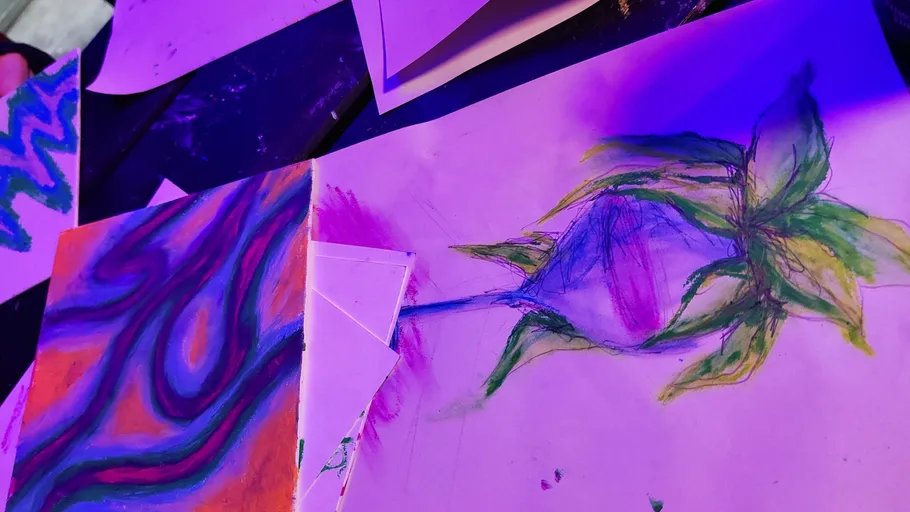 Bunte abstrakte Zeichnungen auf Papier unter lila Licht.