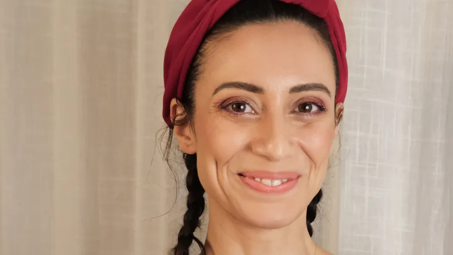 Smiling person with braided hair and headband.