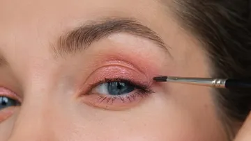 Auge mit rosa Make-up und Pinsel, der Eyeliner aufträgt.