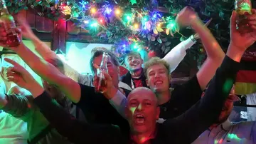 People celebrating with drinks and colorful lights.