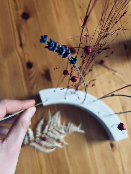 Hand arrangiert getrocknete Blumen auf Holztisch.