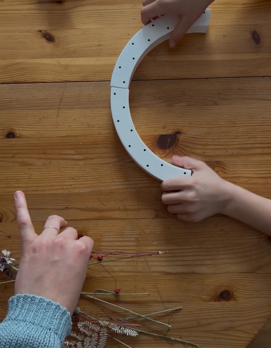 Hands arranging semi-circle on wooden table.