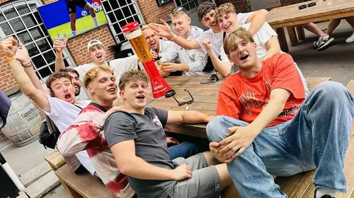 Group of friends cheering at outdoor table.