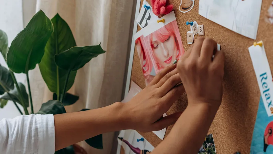 Hands pinning photos on corkboard.