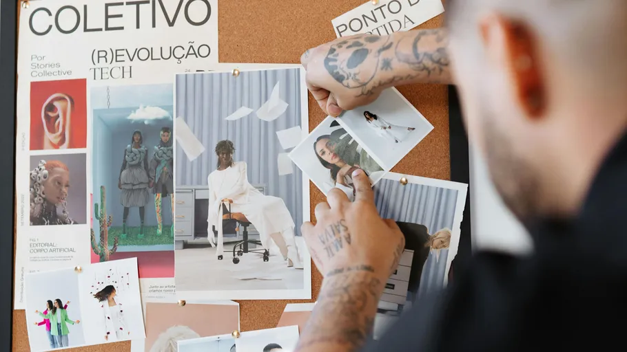 Person arranging photos on a cork board.